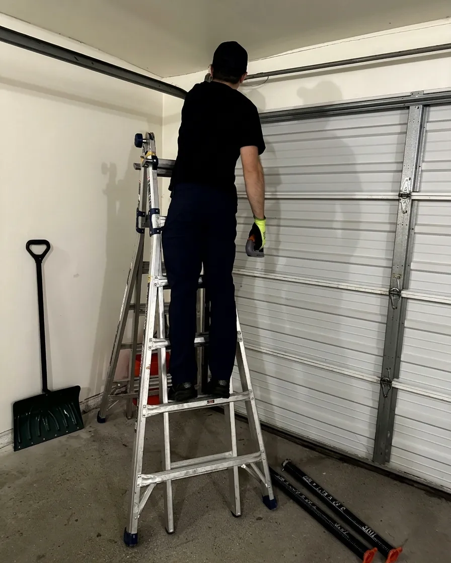Goldman’s technician replacing garage door springs on a ladder
